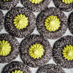 Chocolate thumbprint cookies rolled in sparkling sanding sugar, filled with a bright green piped mint matcha buttercream center.