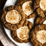 Pumpkin cookies with cream cheese centers on a white speckled ceramic platter. The cookies are dusted with cinnamon and coarse golden Turbinado sugar.