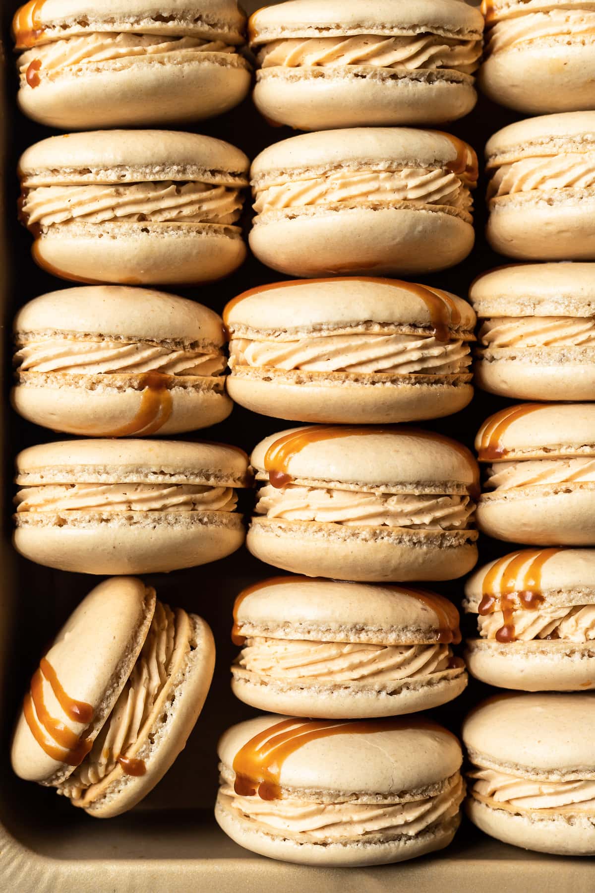 Macarons lined up in columns in a gold pan.