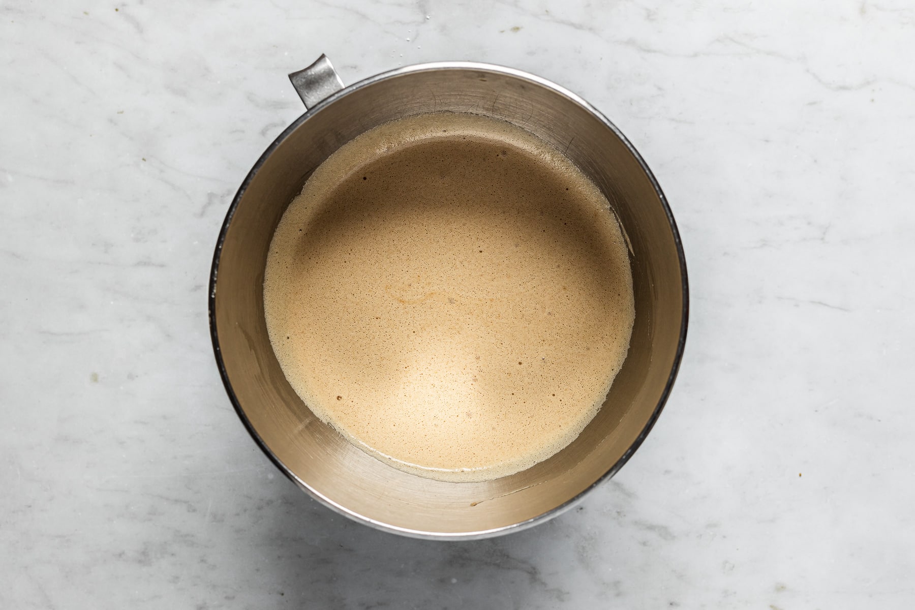 A mixing bowl with egg whites and brown sugar mixed together.