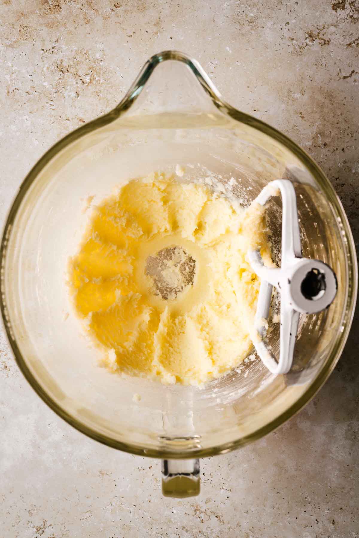 A clear glass mixing bowl with creamed butter and sugar for muffins.