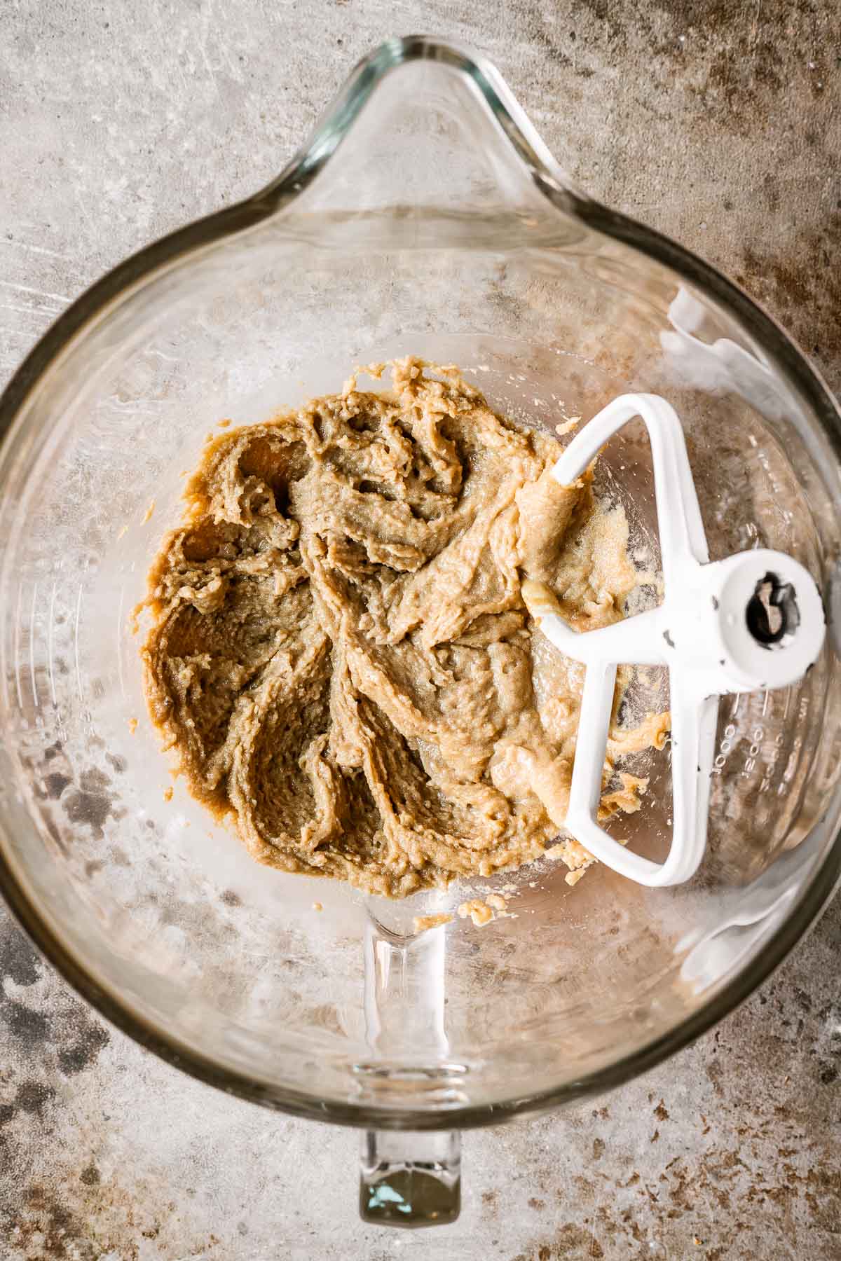 A glass bowl filled with wet ingredients for cookie dough.