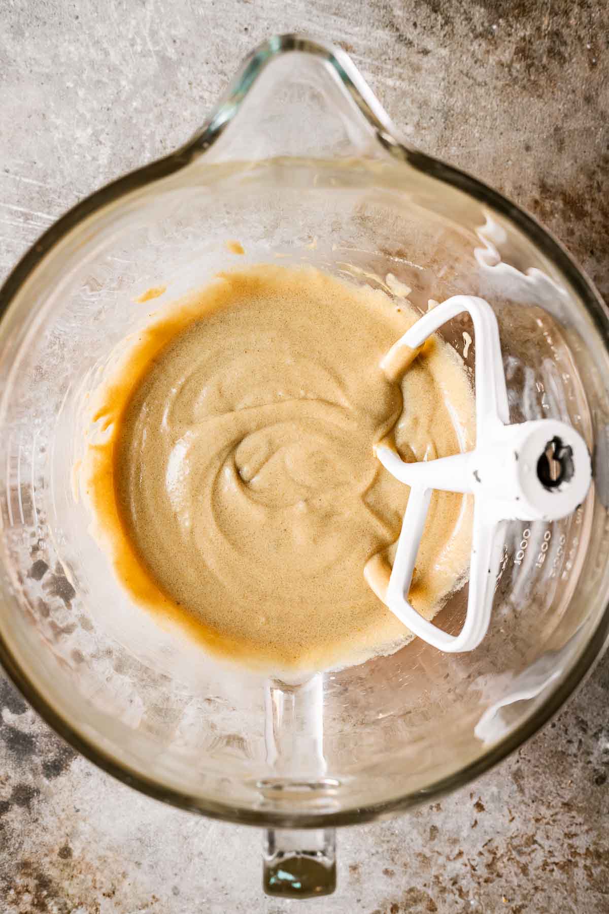 A glass mixing bowl with beaten butter, sugar and peanut butter.