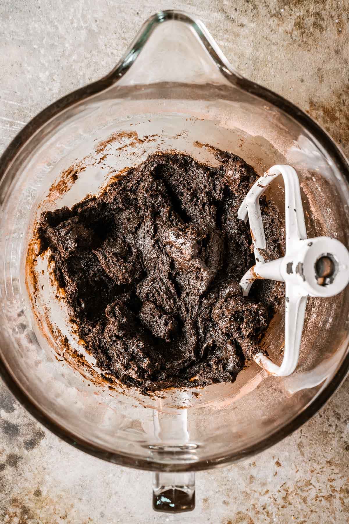 A glass bowl filled with dough for dark chocolate cookies.