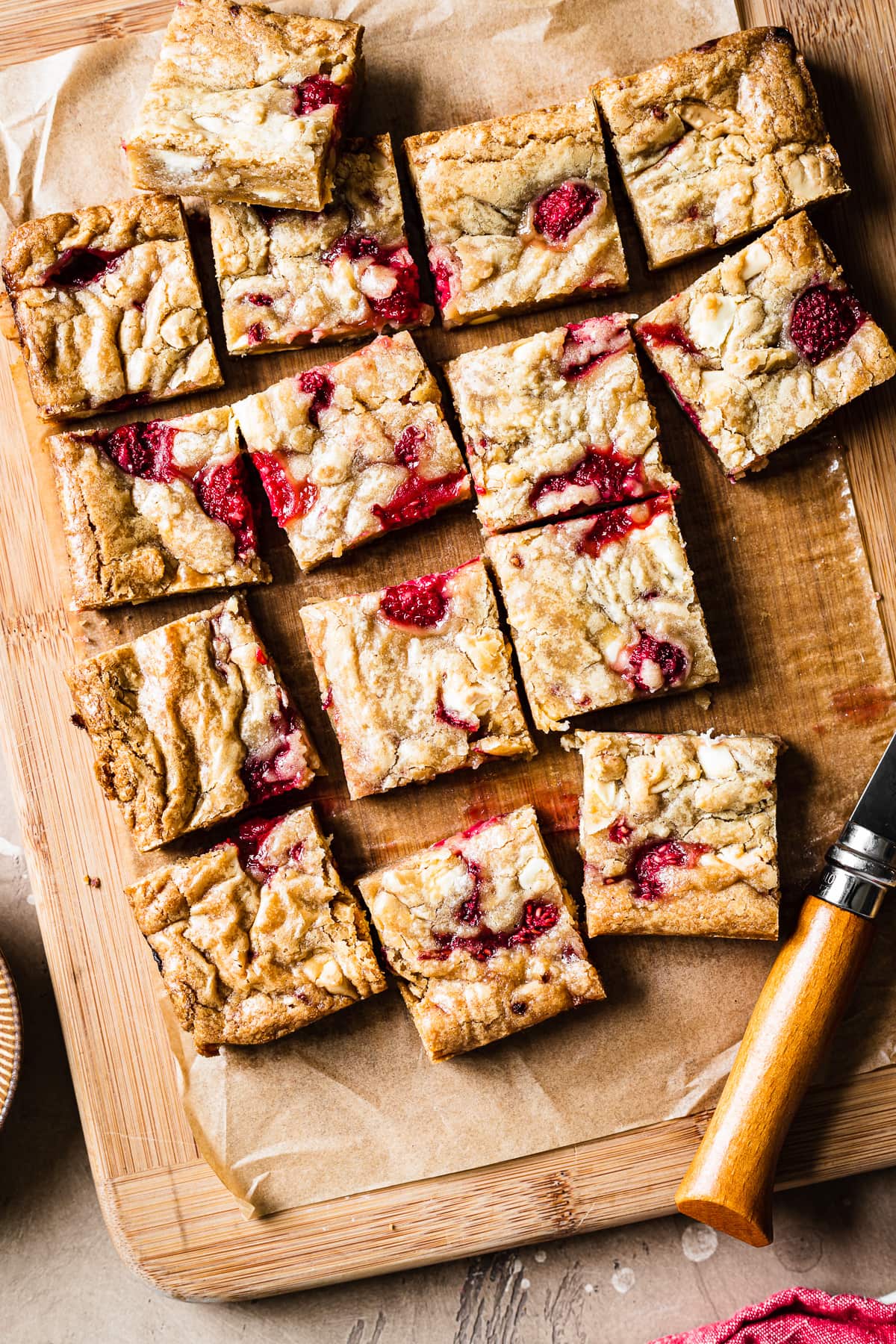 Bar cookies cut into squares on a wooden cutting board with knife resting nearby.