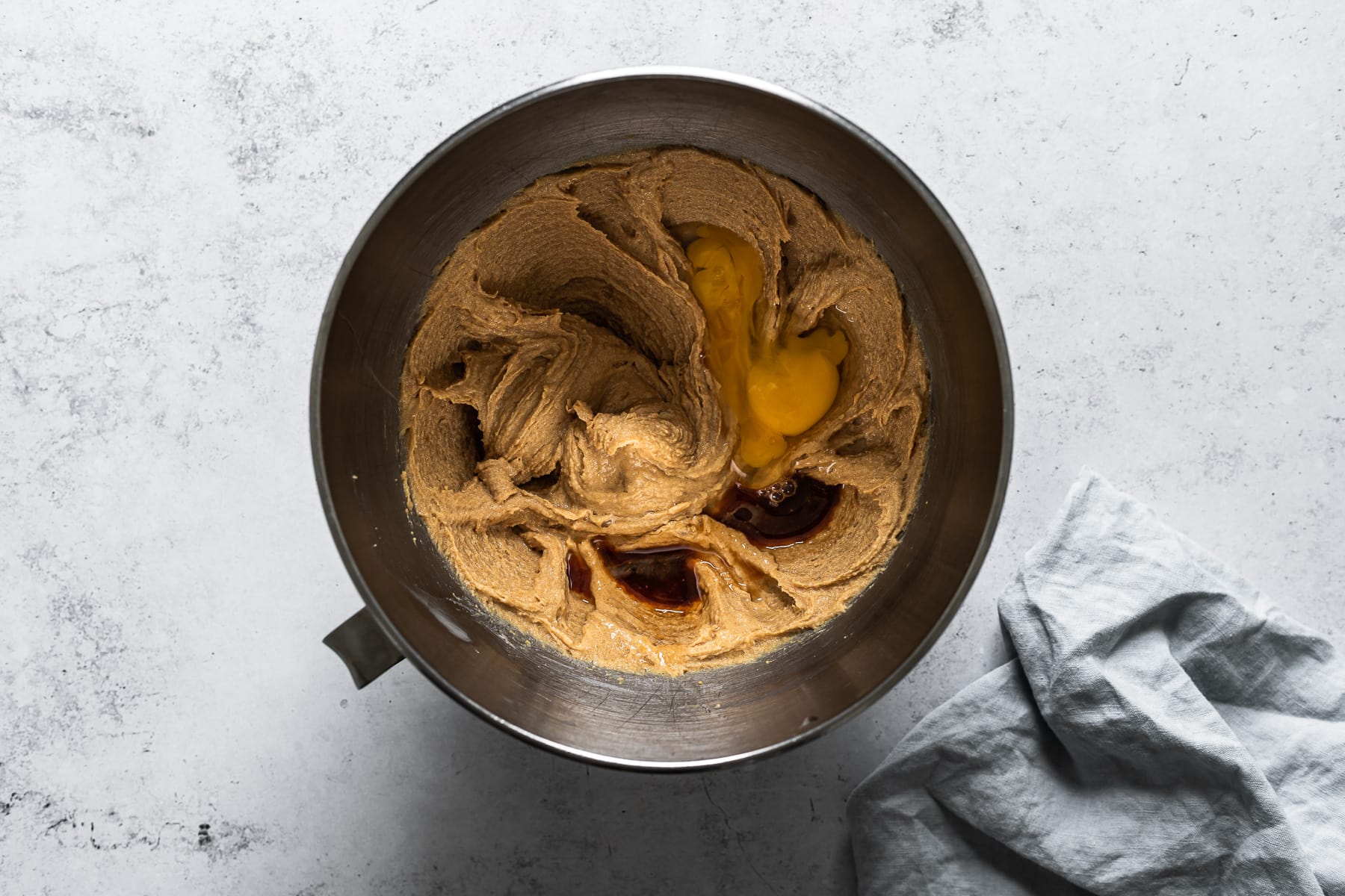 Process photo of a bowl of cookie dough with eggs and vanilla added.