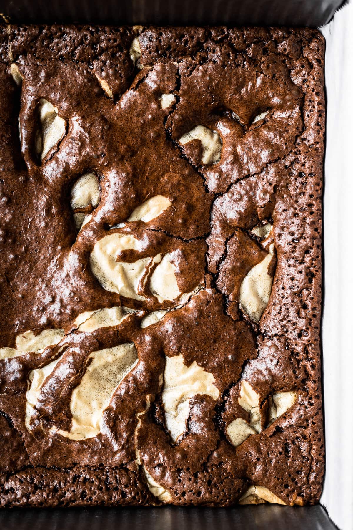 A pan of brownies with blondie batter swirled throughout in a marble pattern. The crust has a shiny, crackly top.