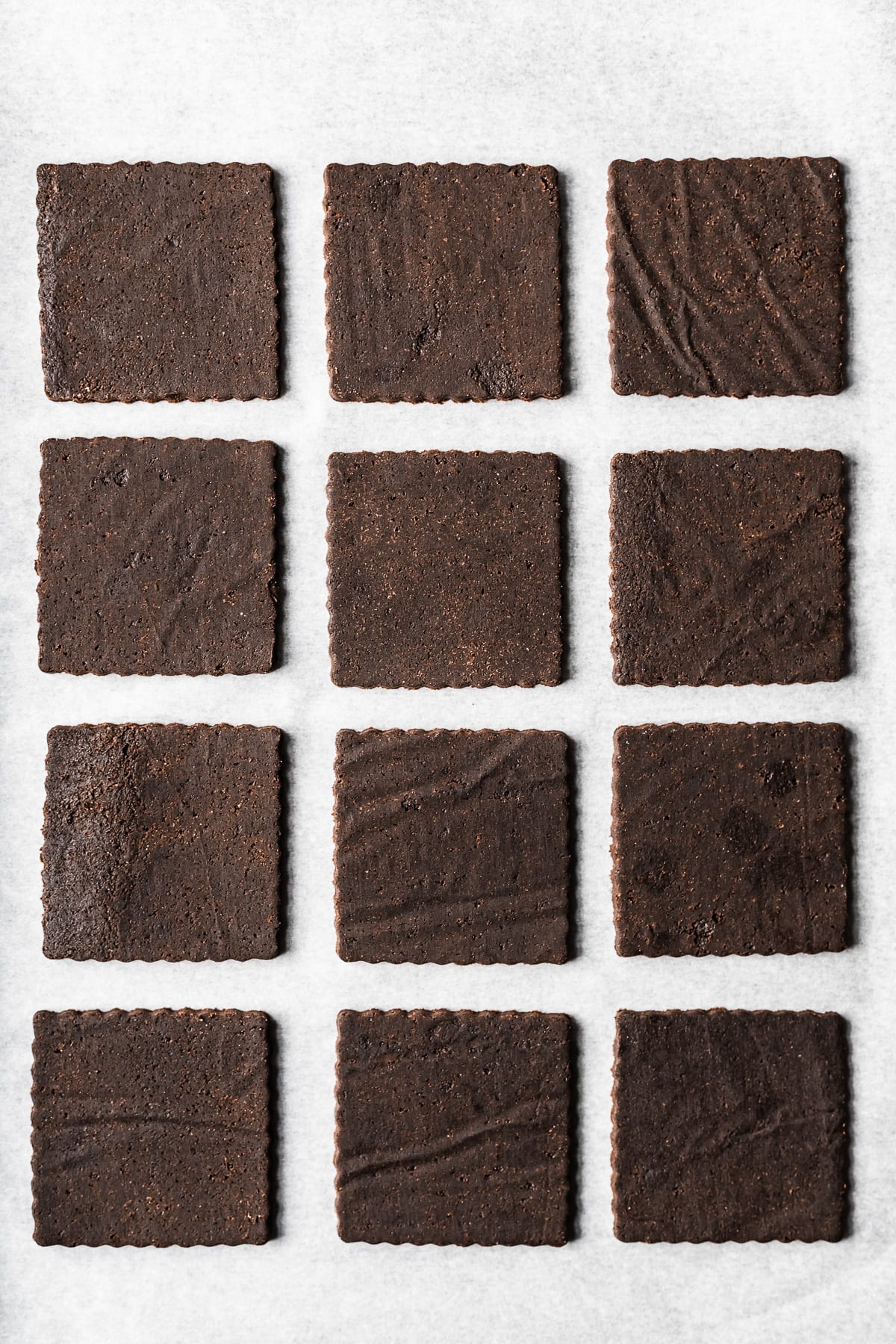 Unbaked square cookie dough cutouts on white parchment paper.