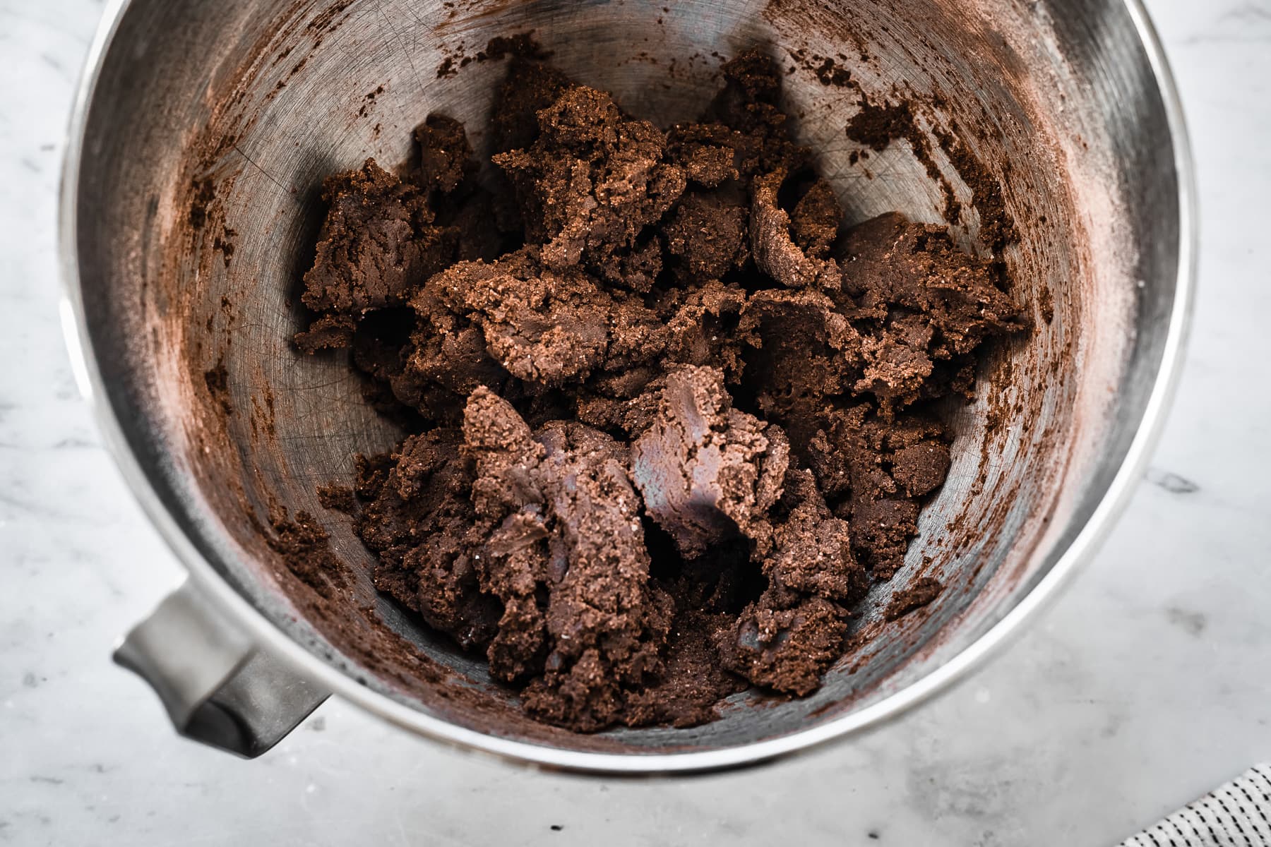 Process photo showing finished dough for chocolate wafer cookies in a metal mixing bowl on a marble surface.