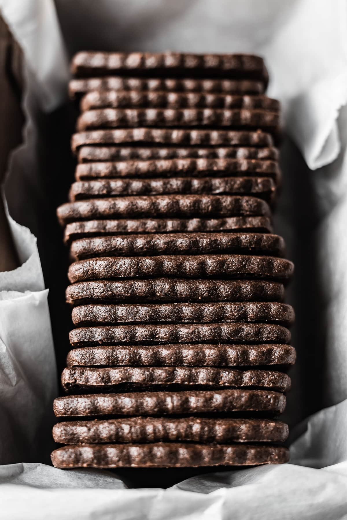 A top view of a row of chocolate wafer cookies in a white parchment paper lined container.