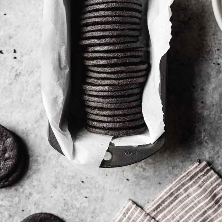 A row of round dark chocolate cookies in a parchment lined pan.