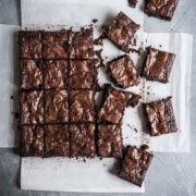 Top view of cut squares of brownies on white parchment paper on a grey stone background