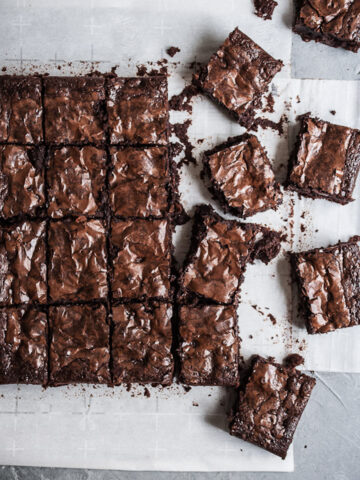 Top view of cut squares of brownies on white parchment paper on a grey stone background