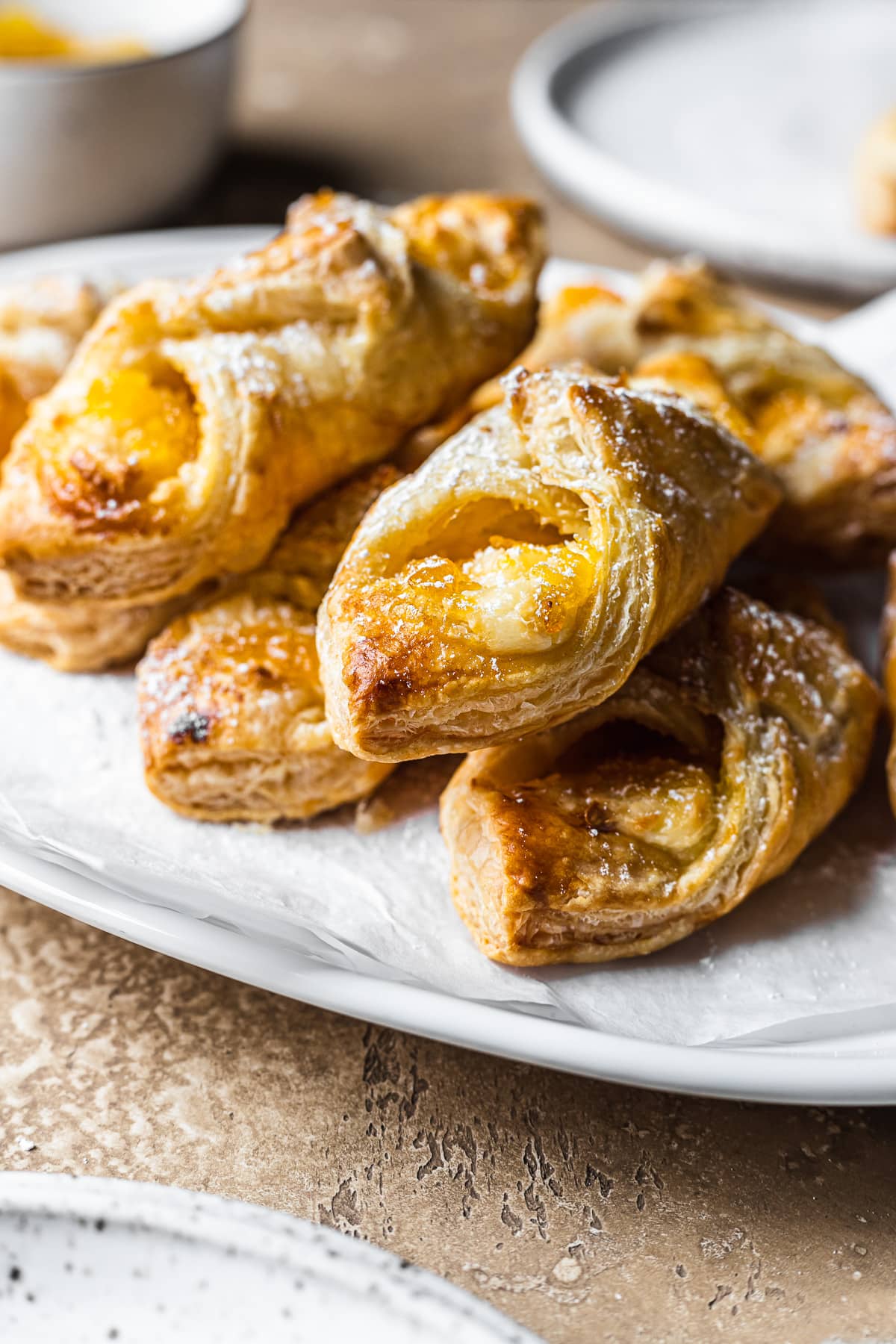 A close up photo showing Puerto Rican quesito pastries stacked on a white ceramic plate.