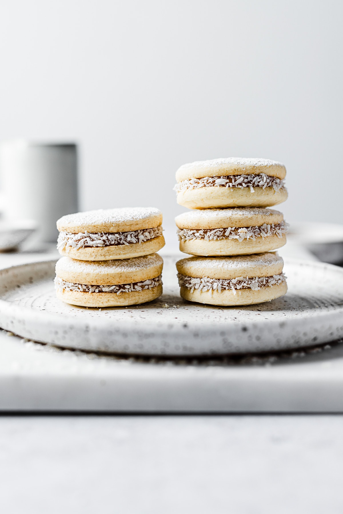 Two stacks of Argentine alfajores de maicena on a white ceramic plate resting on a white marble board.