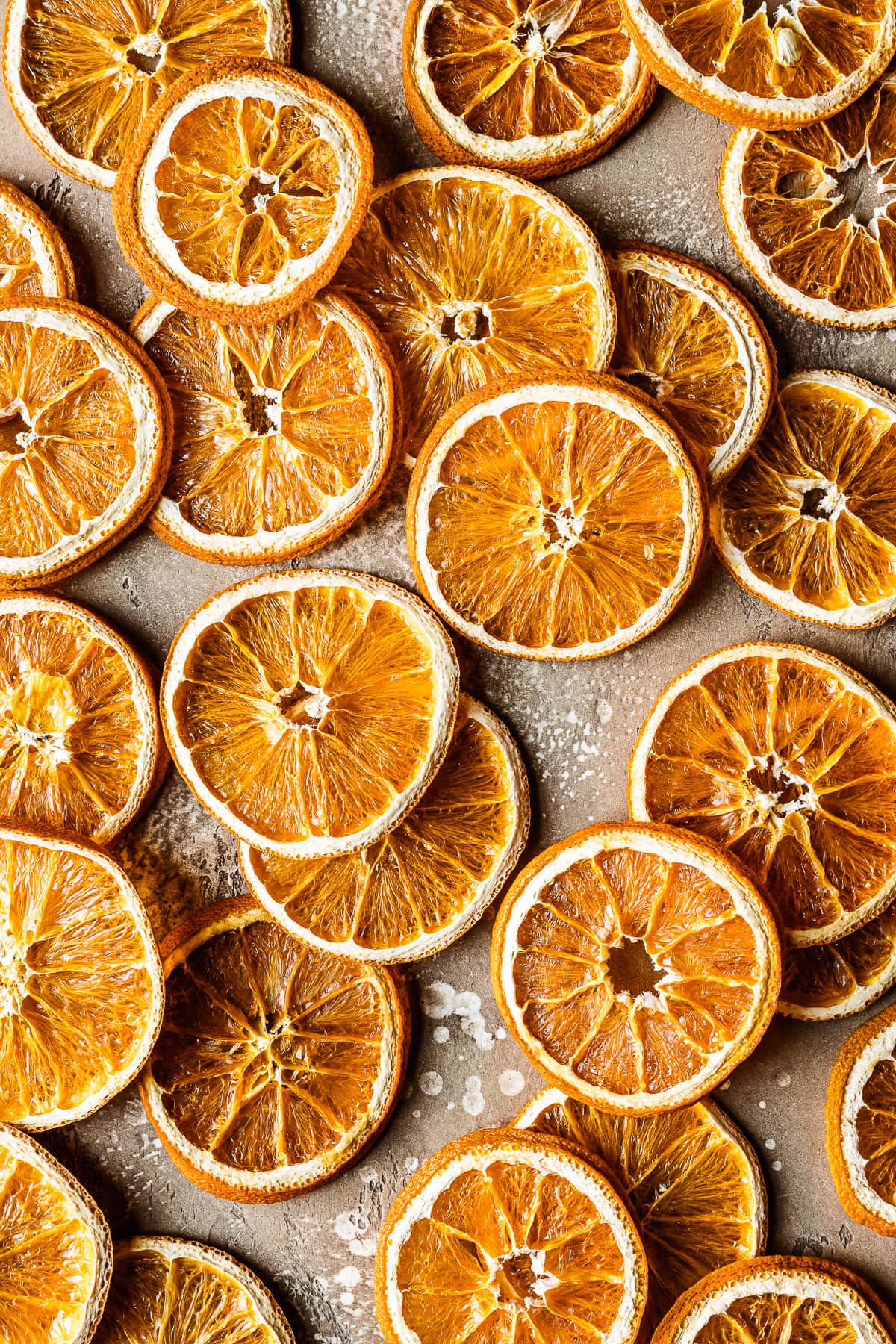 Dried orange slices on a speckled tan stone background.