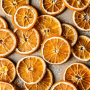 Dried orange slices on a speckled tan stone background.