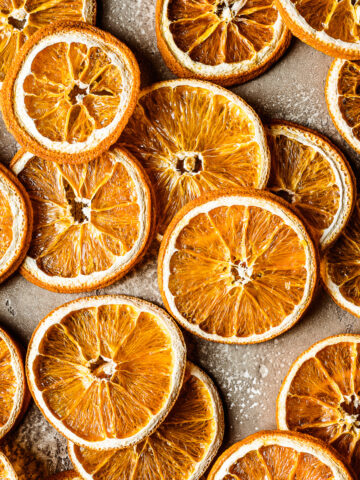 Dried orange slices on a speckled tan stone background.