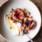 Grilled peaches with creamy cheese and honey in a low bowl with a spoon.