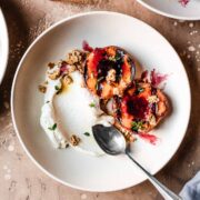 Bowls of grilled peaches with mascarpone cream on a warm tan surface.