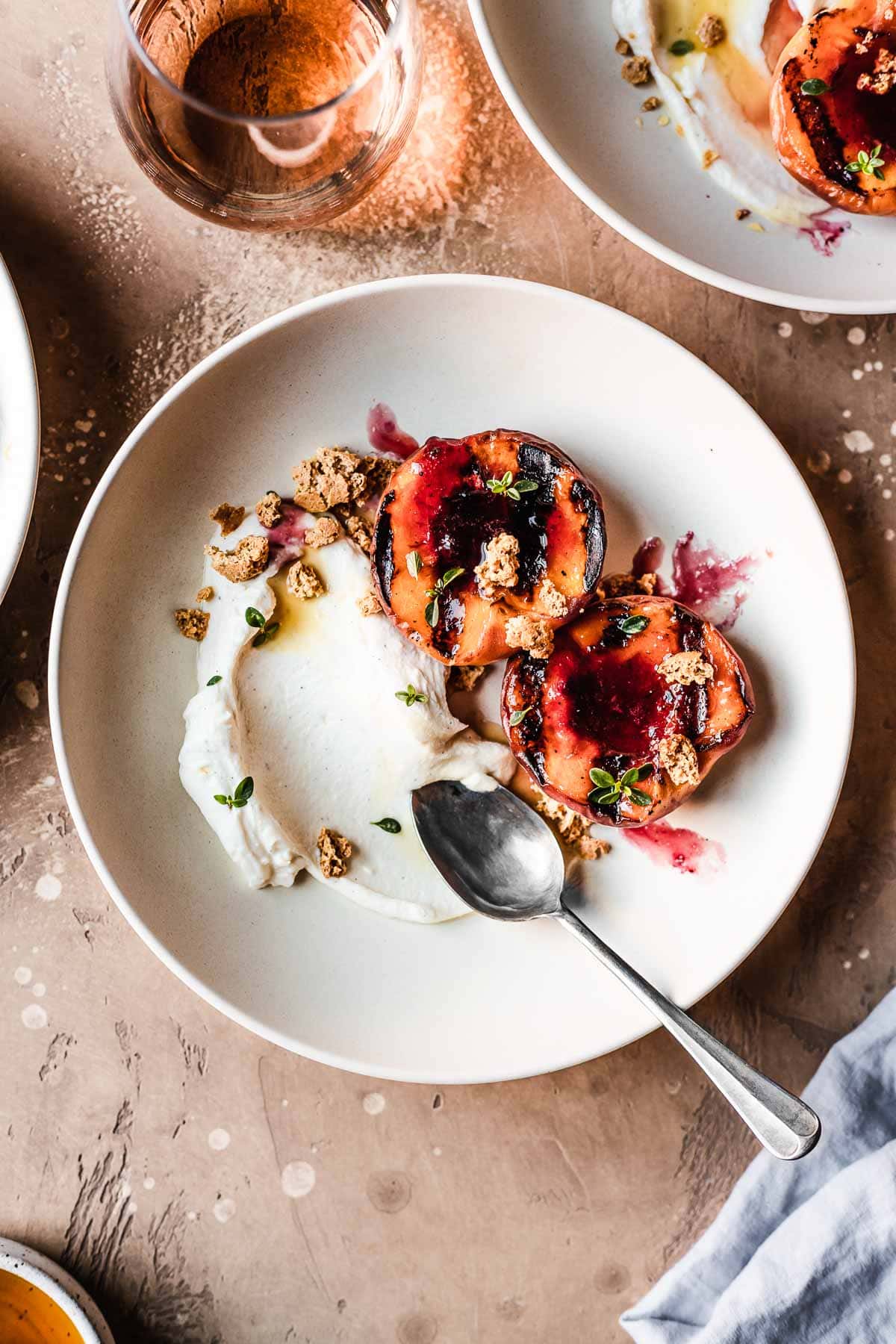 Bowls of grilled peaches with mascarpone cream on a warm tan surface.