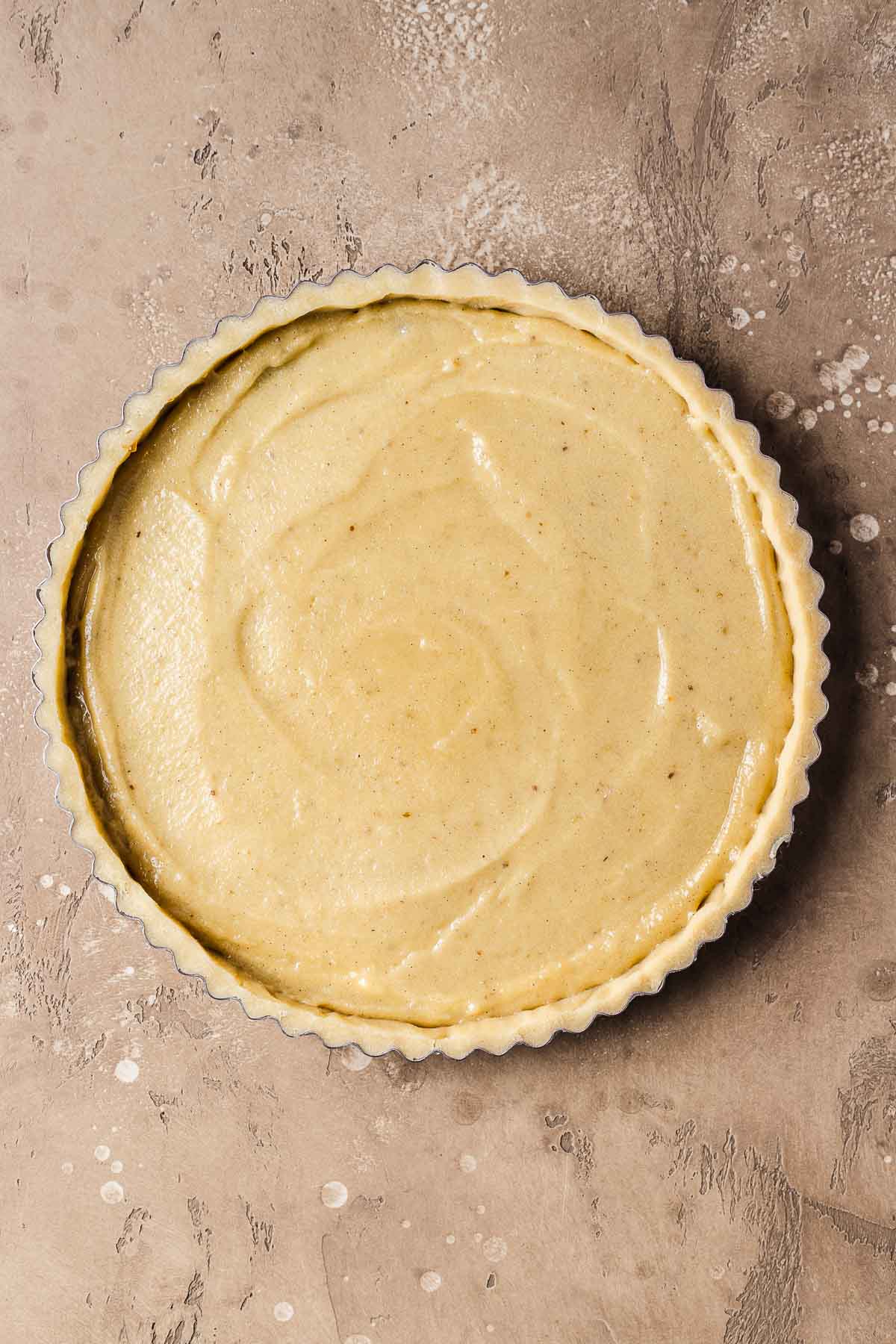 A process photo showing a tart shell filled with almond cream (frangipane).