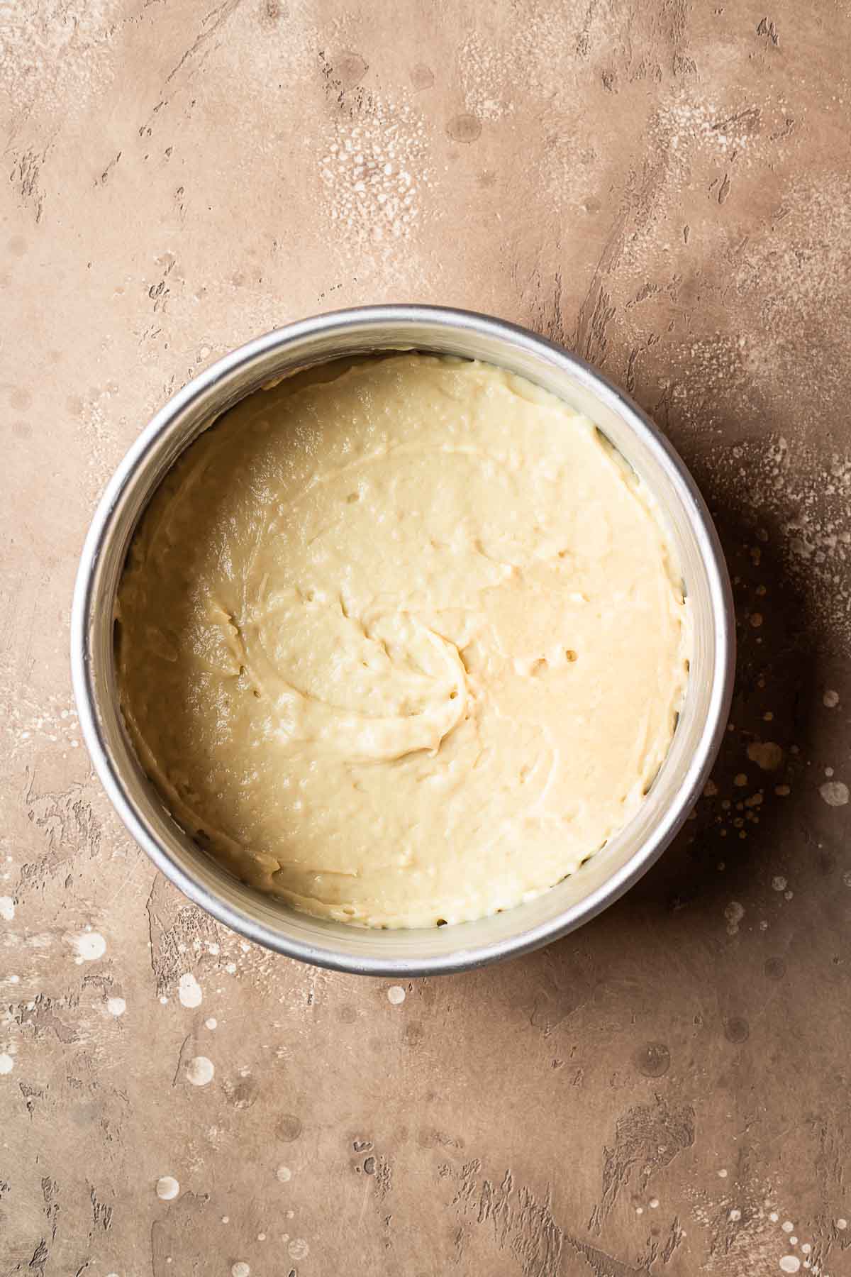 Cake batter leveled and smoothed in a cake pan.