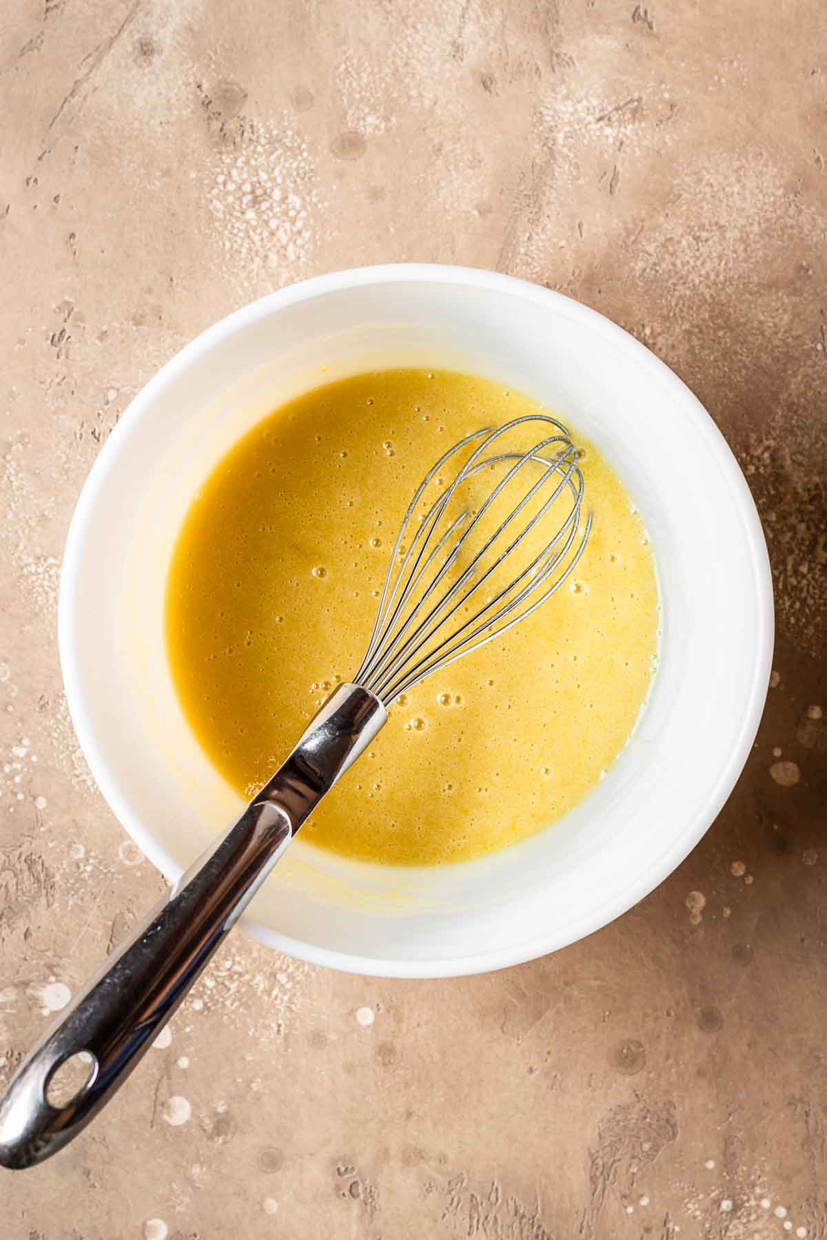 Wet ingredients fully whisked together in a ceramic bowl.