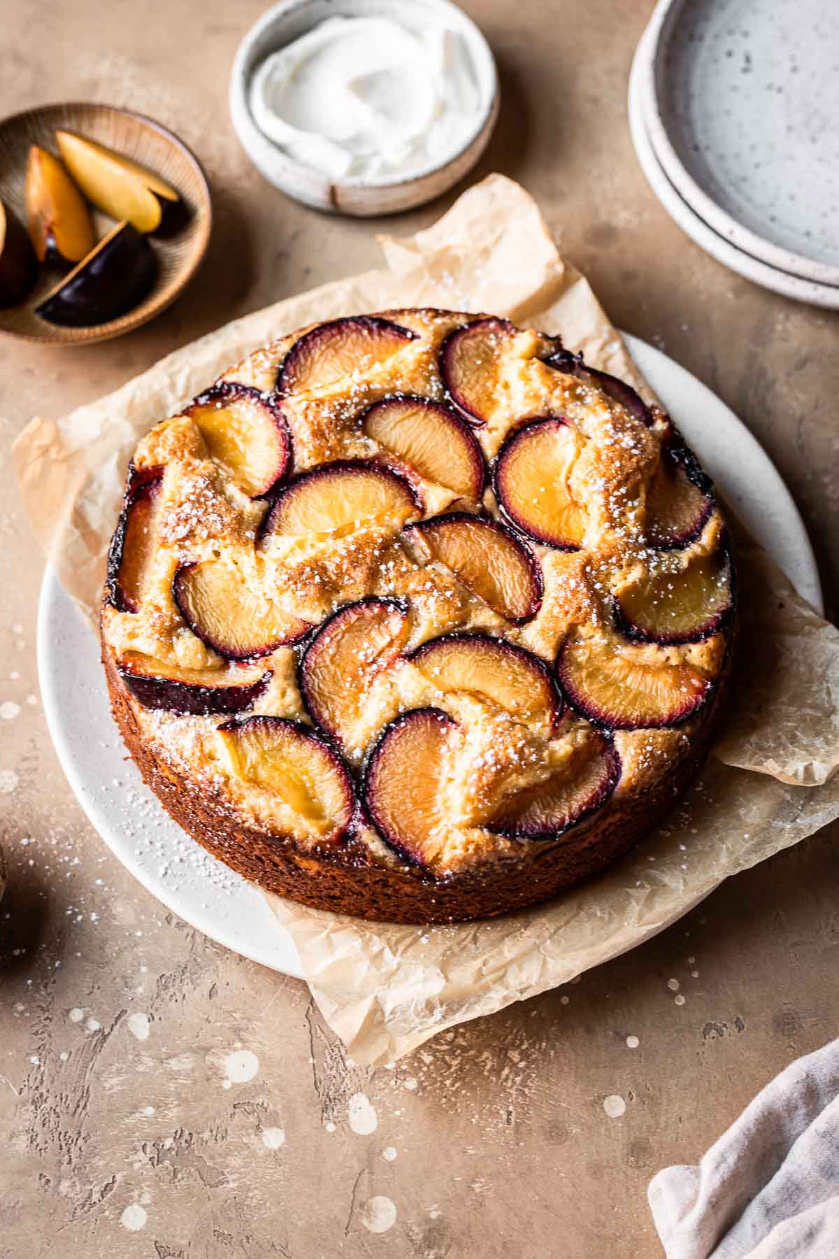 A baked plum and yogurt cake on a parchment lined platter.