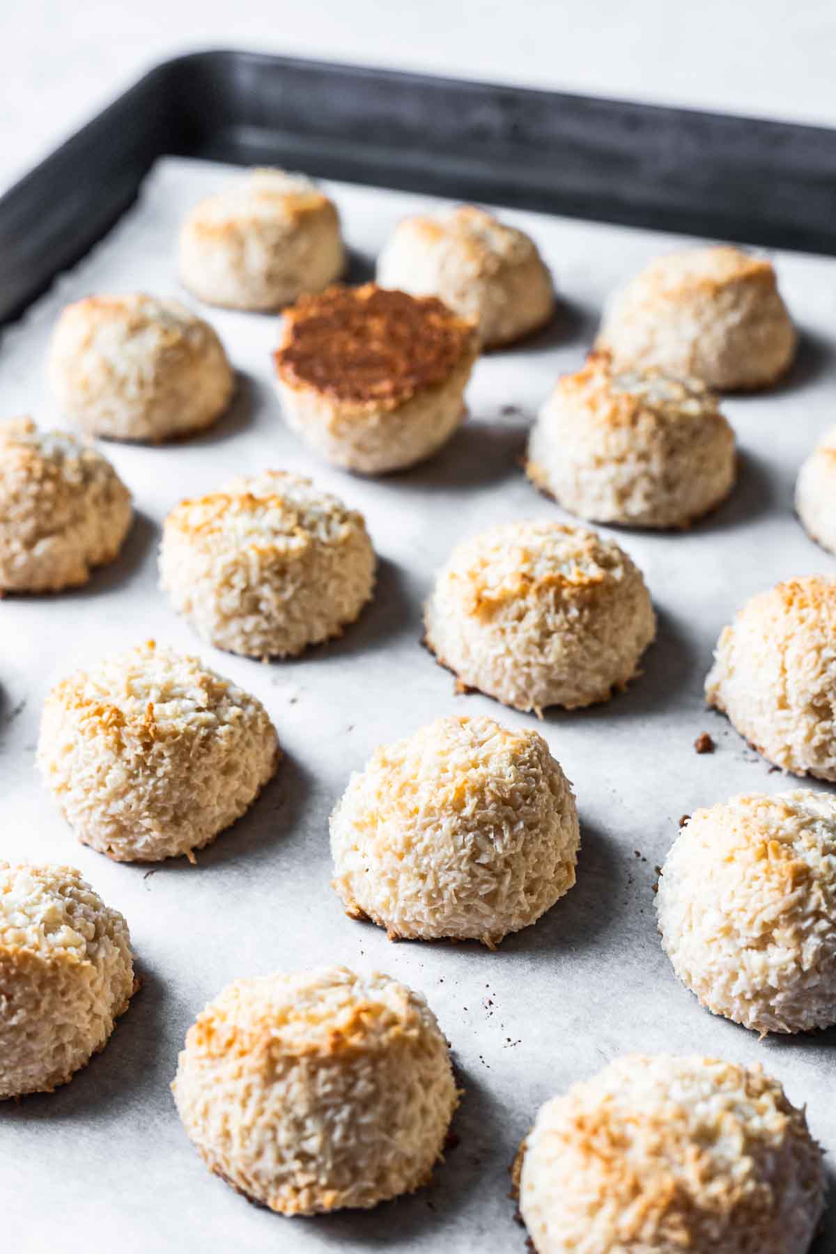 Baked kokosmakronen cookies on a parchment lined baking sheet.