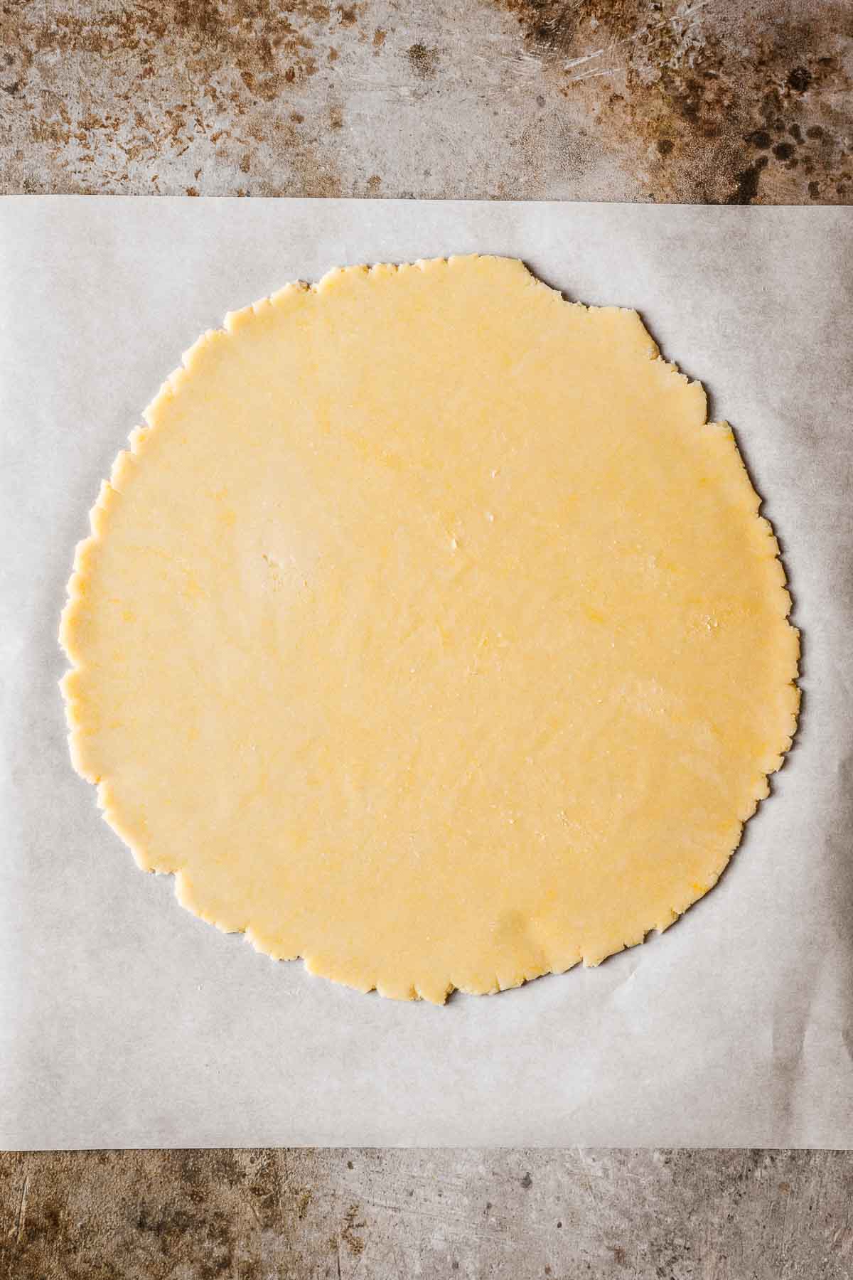 A circle of rolled out dough on parchment paper.