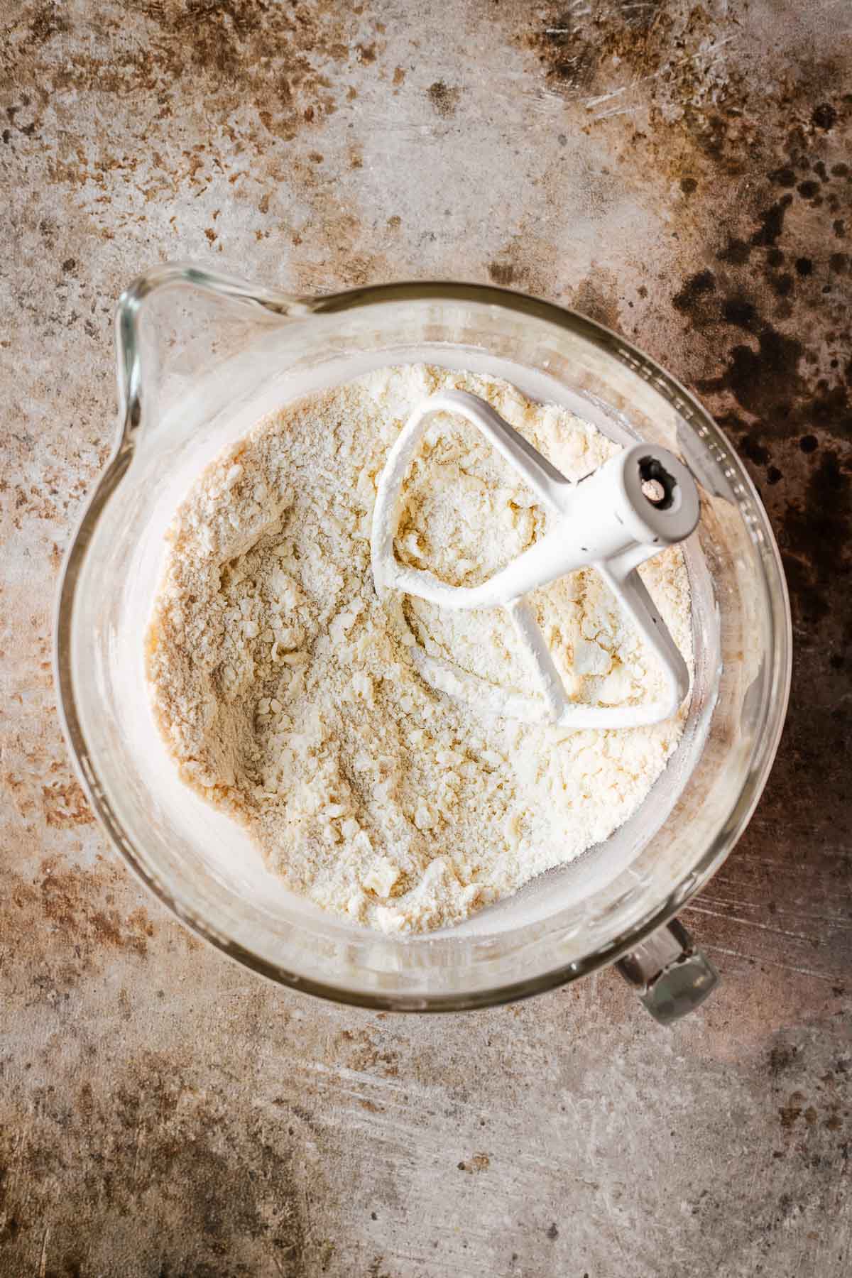 A bowl of dry ingredients mixed with butter and sugar.