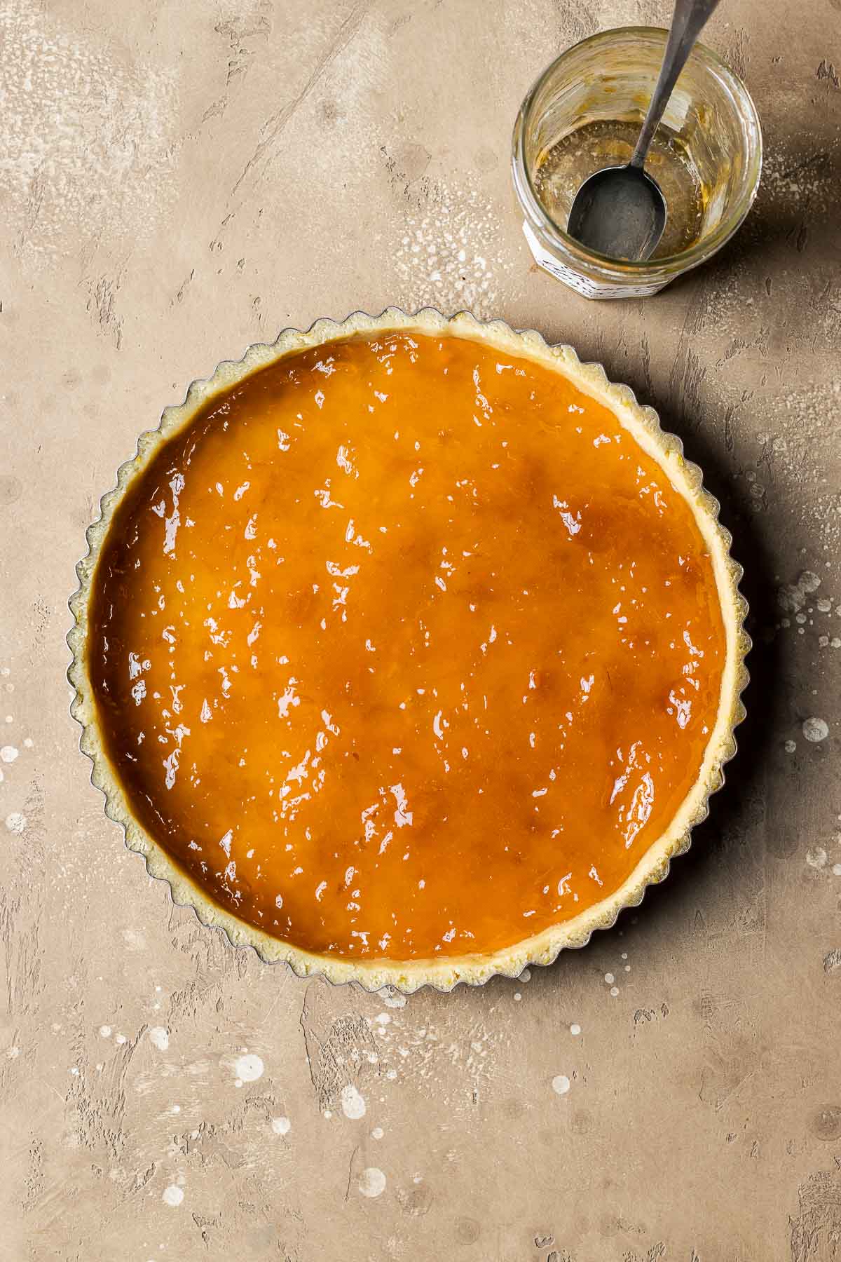 An unbaked tart shell filled with apricot jam.