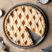 A lattice topped crostata di marmellata with one slice removed.