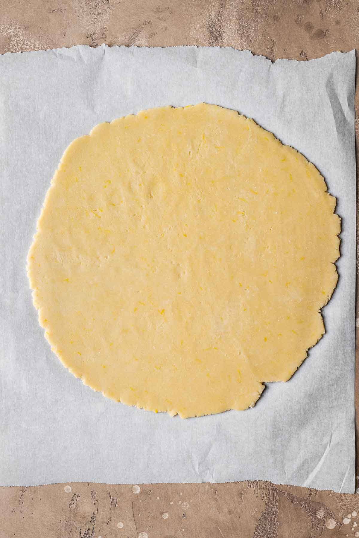 A circle of rolled pastry dough on white parchment paper.