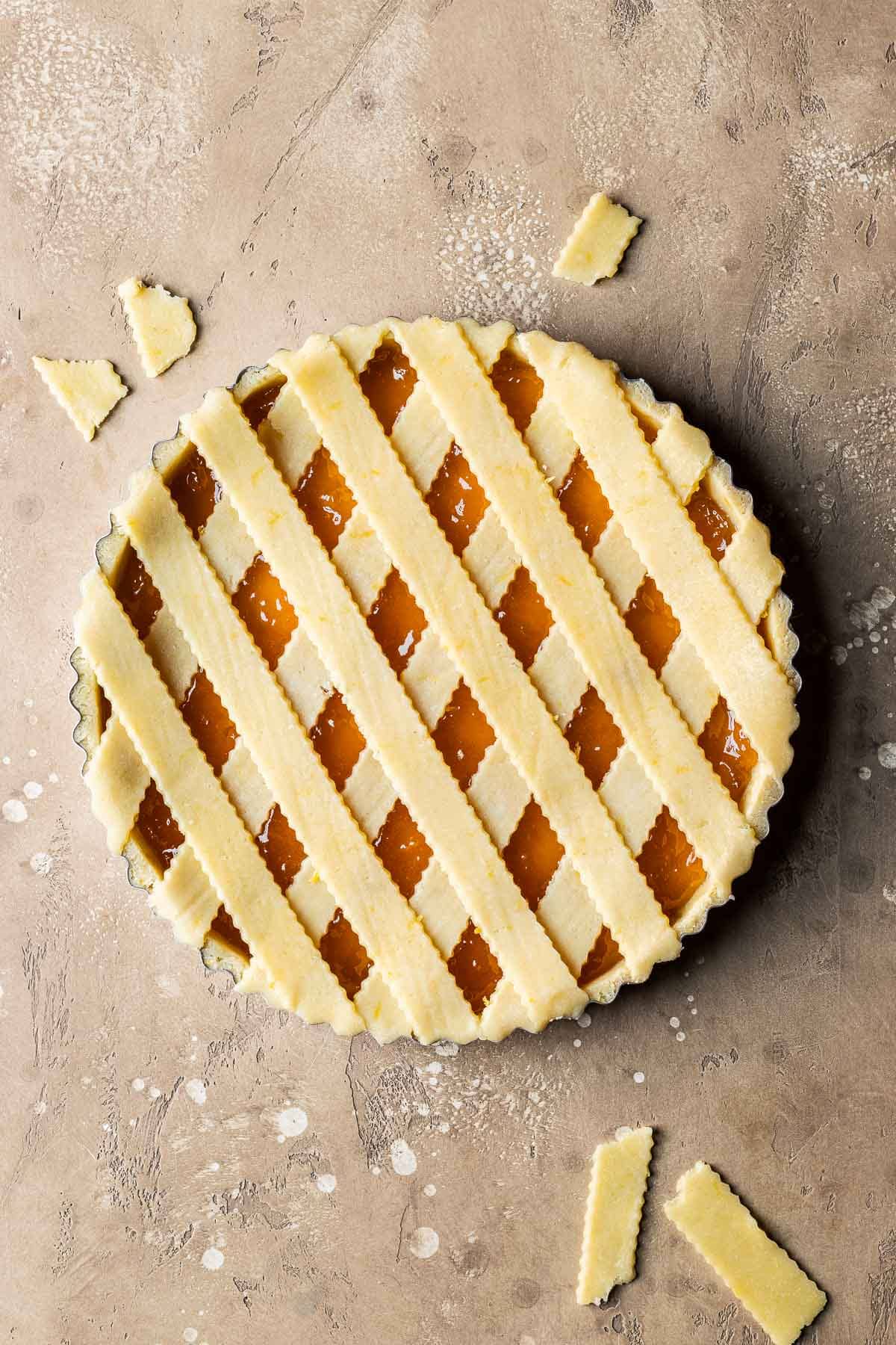 An unbaked crostata di marmellata with strips of lattice dough on top.