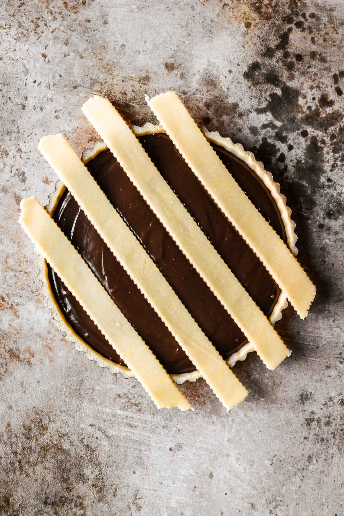 Strips of lattice dough on an unbaked chocolate filled tart.