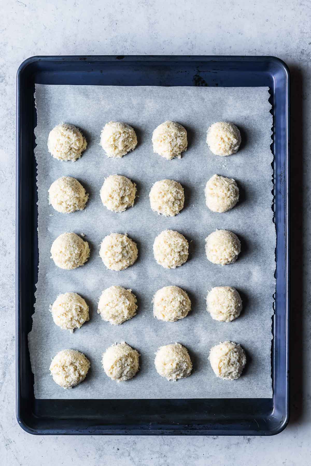 Coconut macaroon dough scooped onto a parchment lined baking sheet.