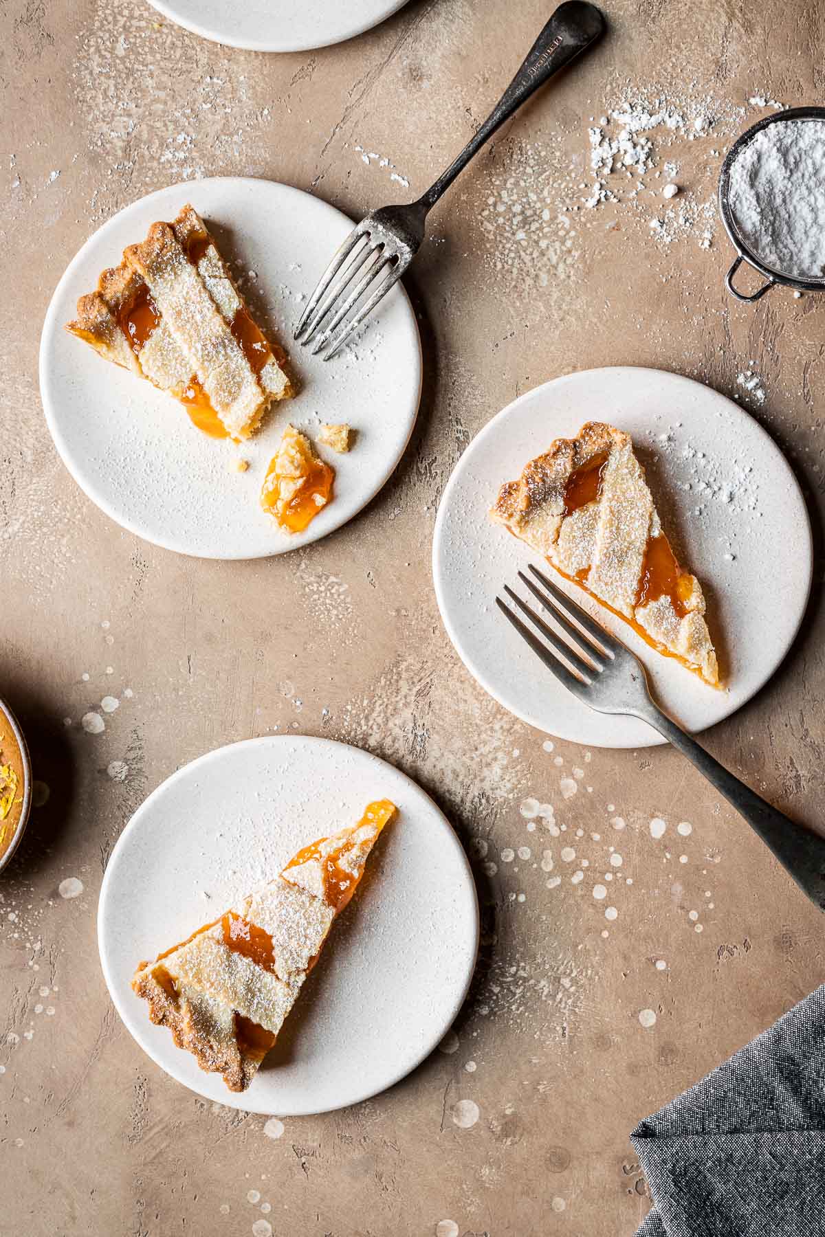 Three slices of lattice topped jam tart on tan plates.