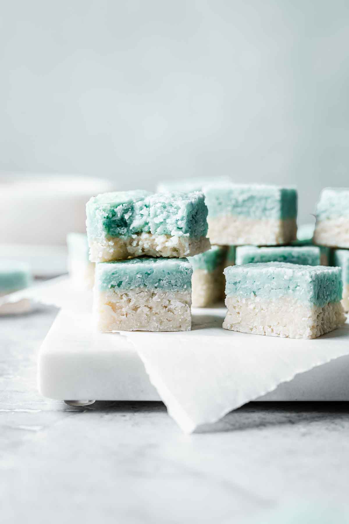 Squares of blue and white coconut ice stacked up with a bite out of one.