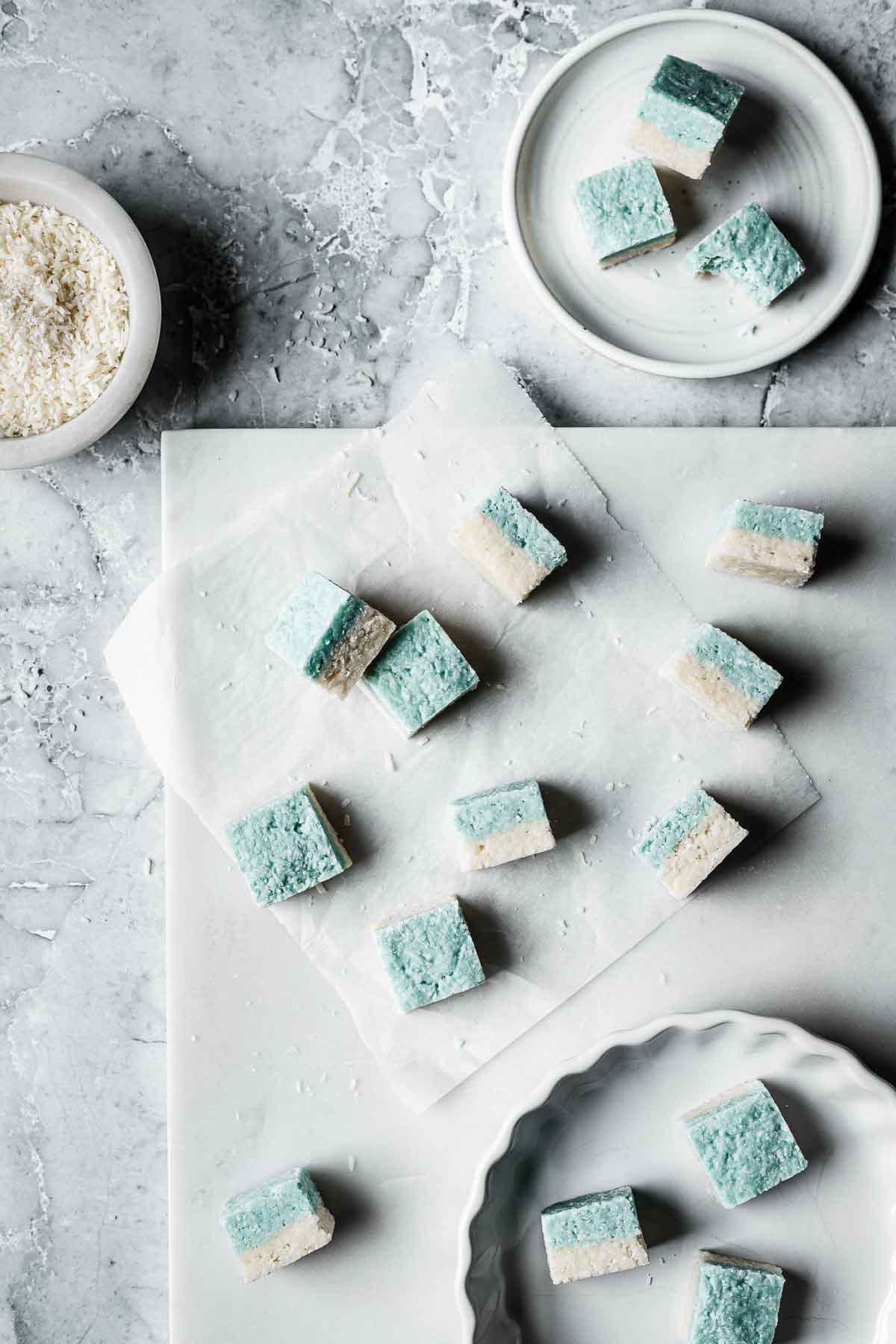 Squares of coconut candy on a white marble tray.