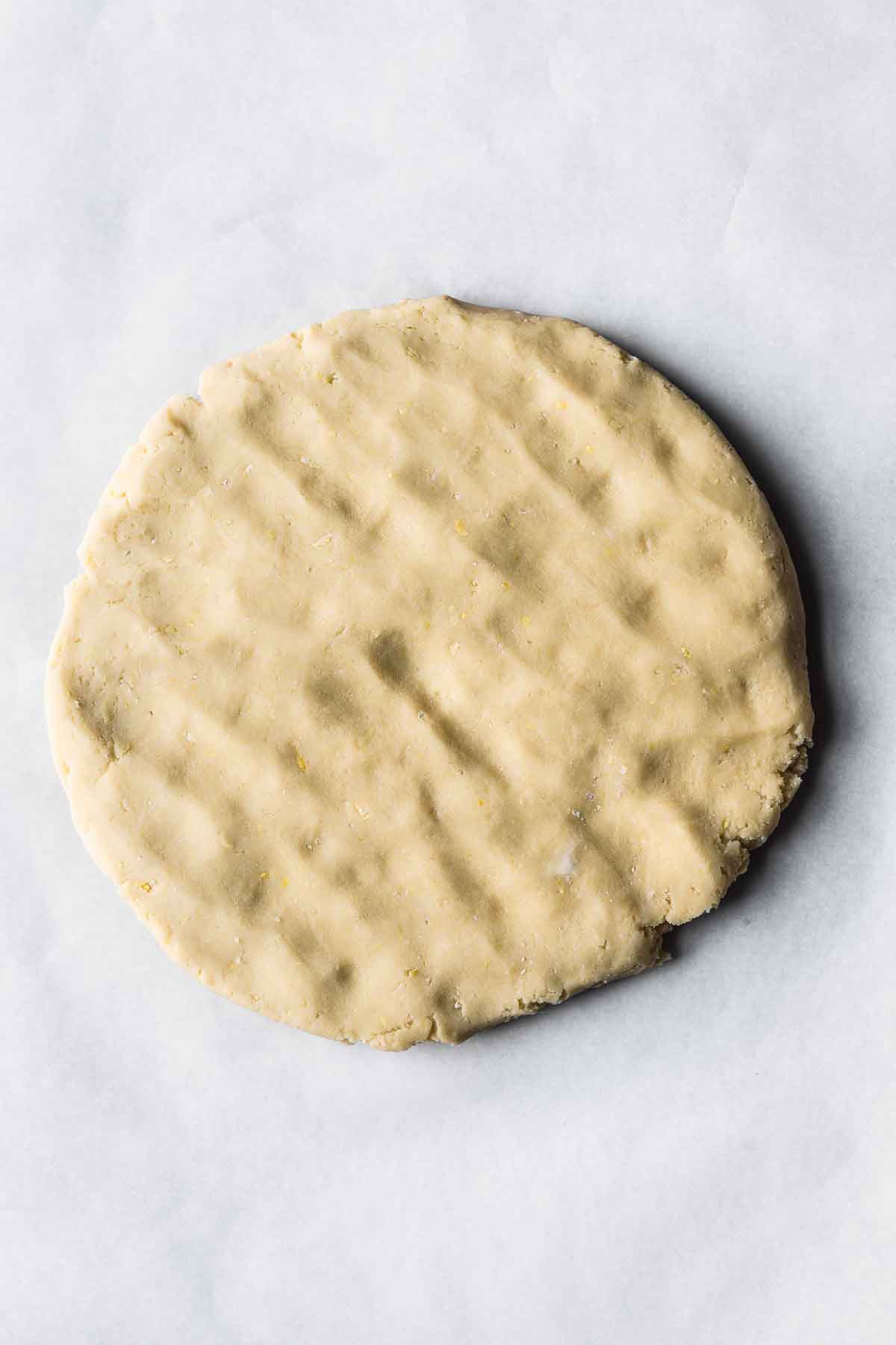 A disc of canestrelli cookie dough on parchment.