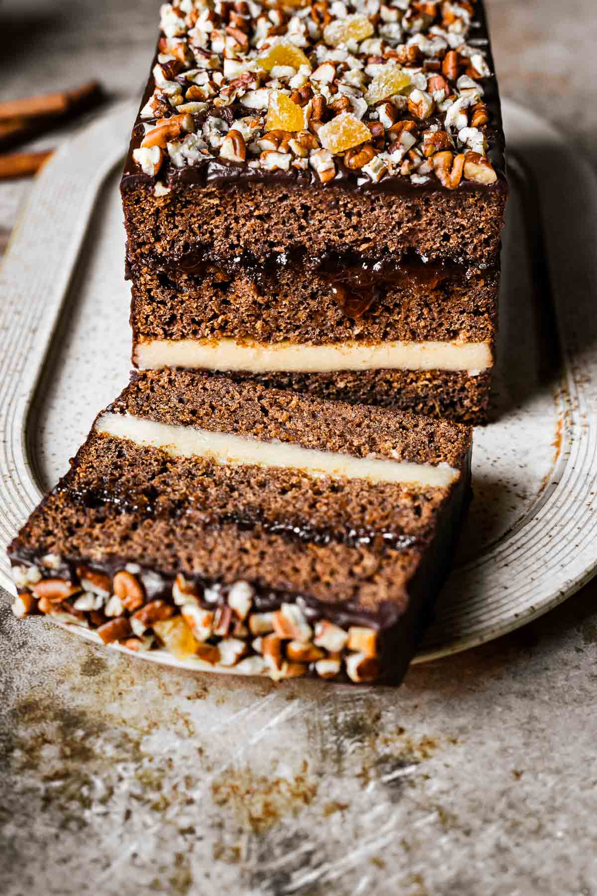 An angled view of a chocolate glazed gingerbread cake revealing the layers.