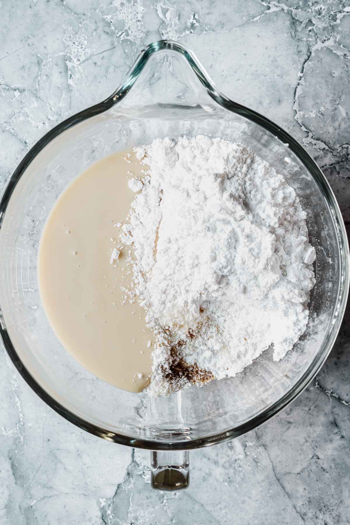 Ingredients for coconut ice recipe in a glass mixing bowl.