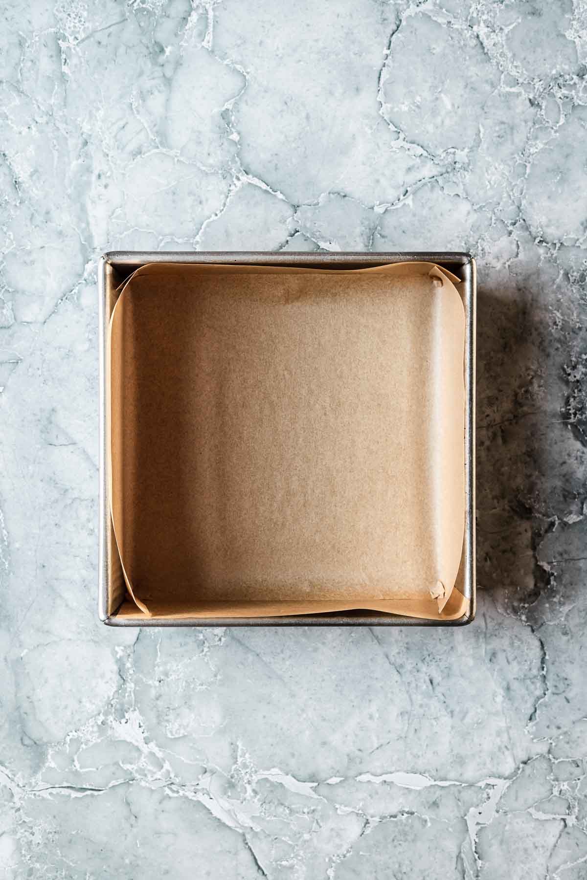 A square baking pan lined with parchment paper.