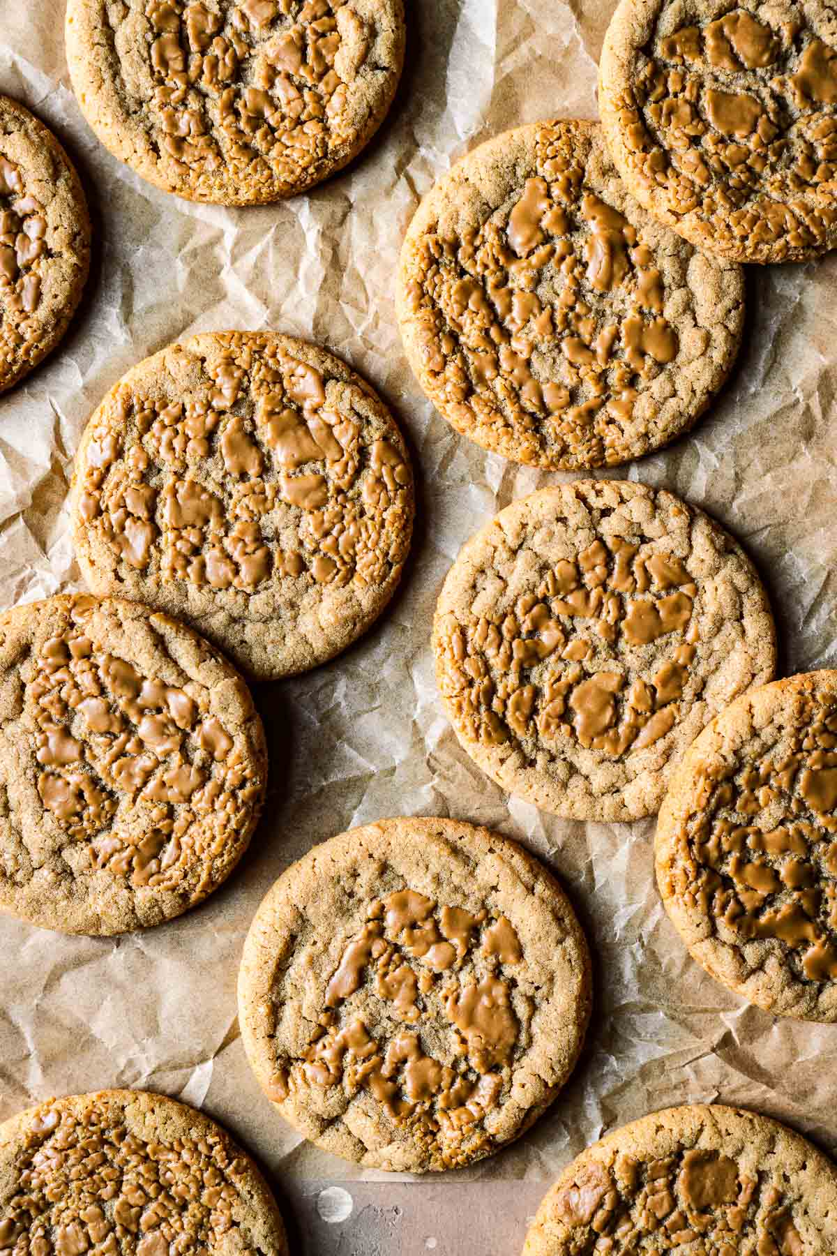 Round brown cookies on crinkled brown parchment paper.