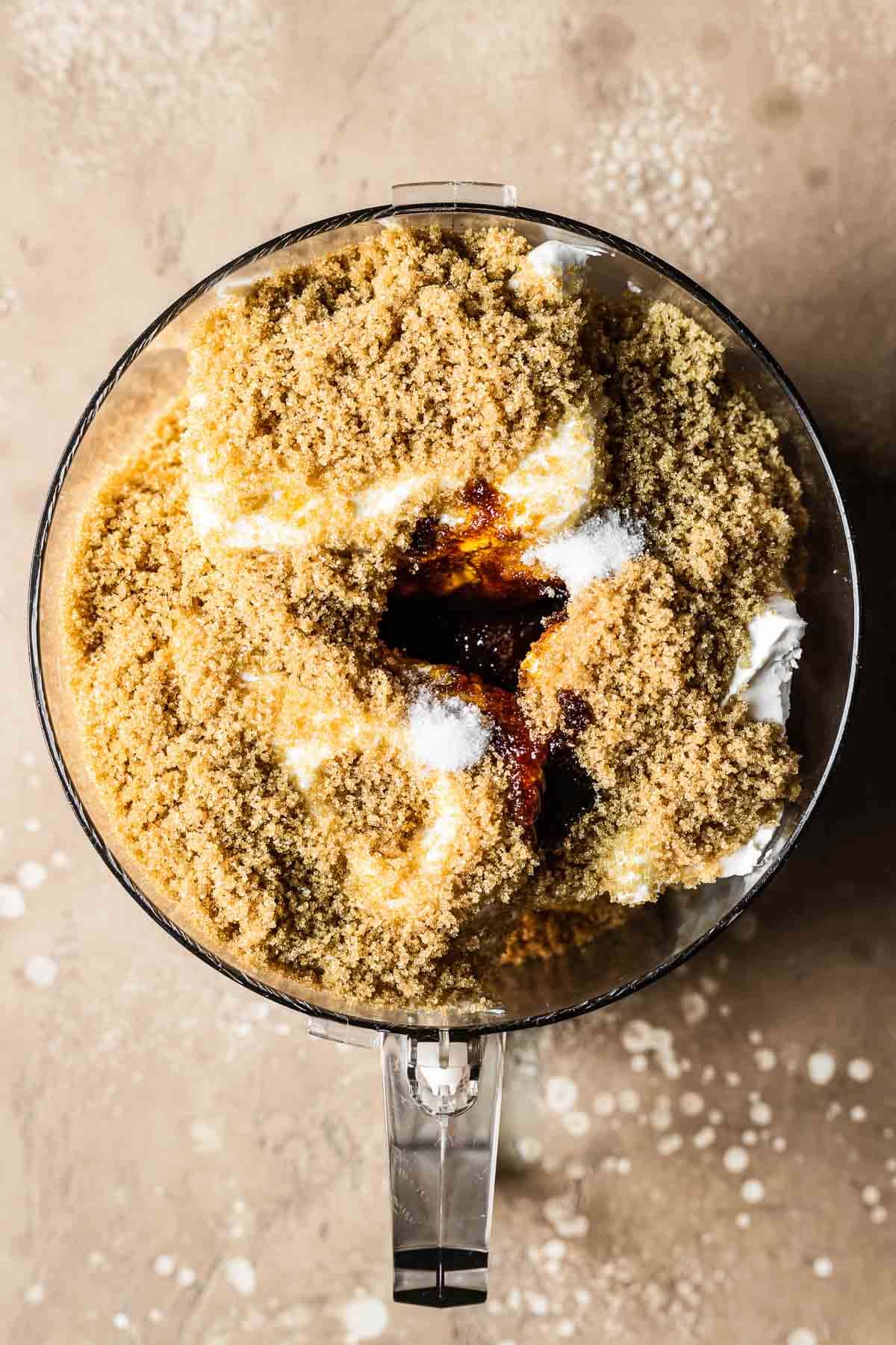 Unmixed gingerbread cheesecake filling ingredients in the bowl of a food processor.