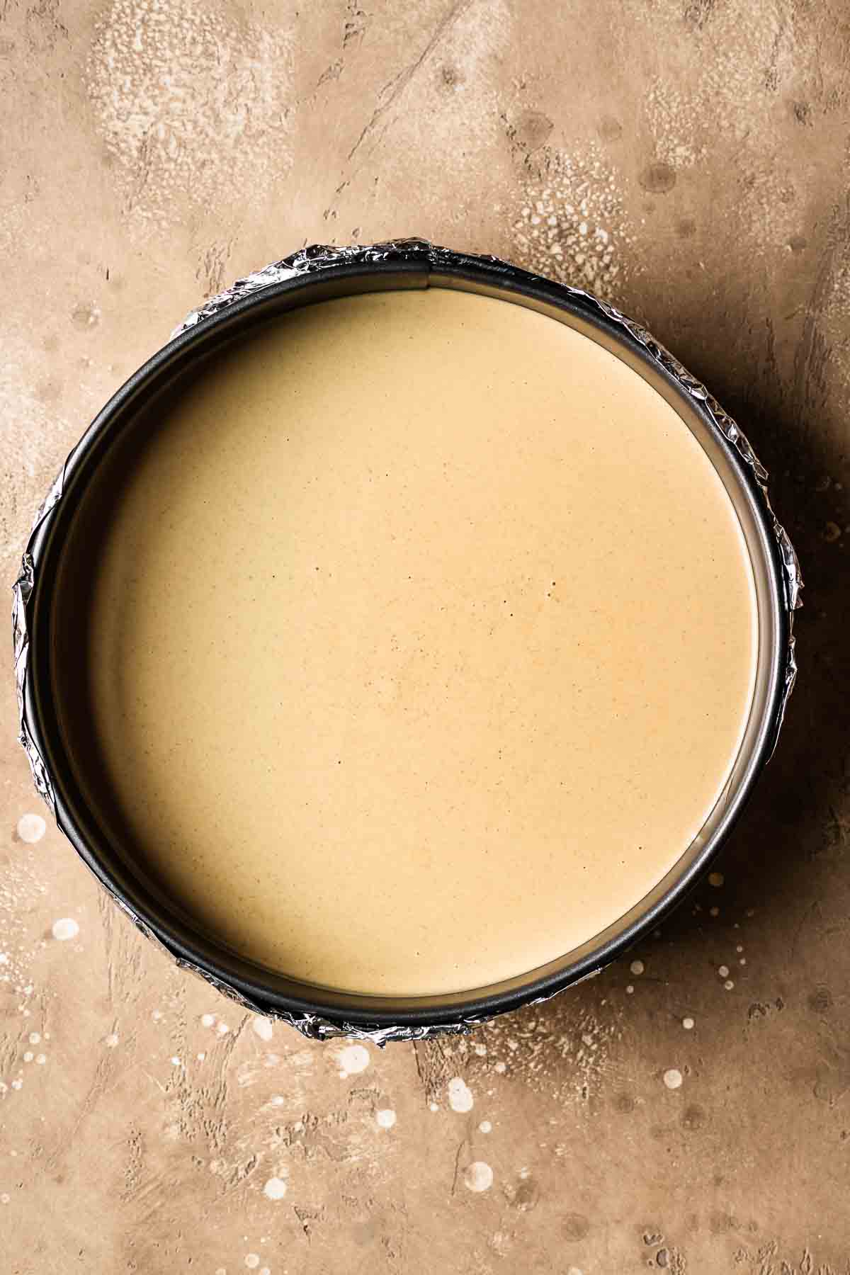 Gingerbread cheesecake batter poured into a springform pan.