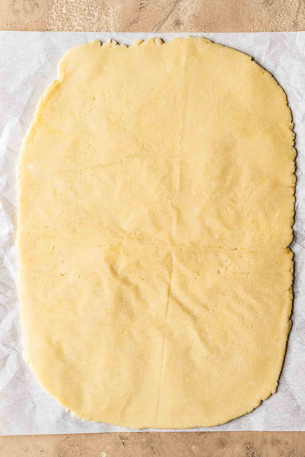 Shortcrust pastry dough rolled out on a piece of parchment paper.