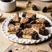 Nussecken bars dipped in chocolate on a white fluted plate.